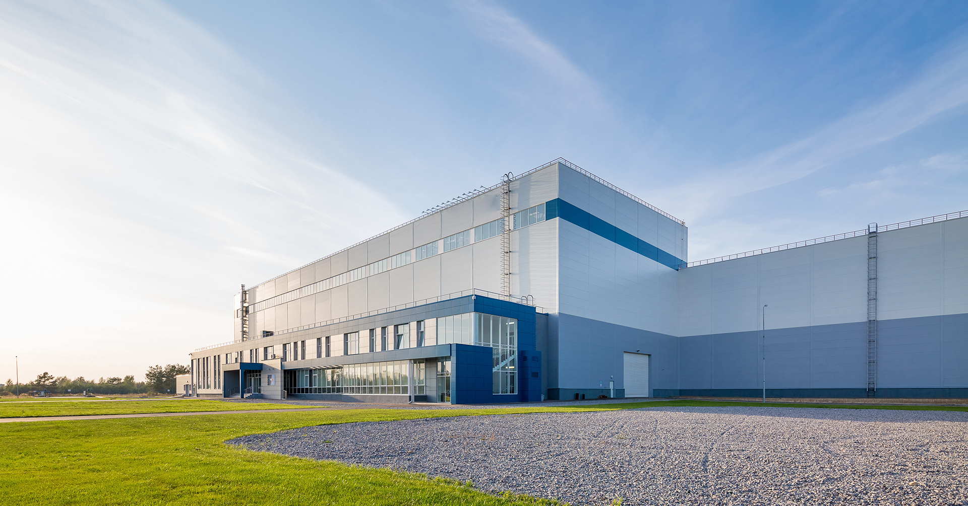 Fabrikgebäude auf einem weitläufigen Grundstück unter blauem Himmel