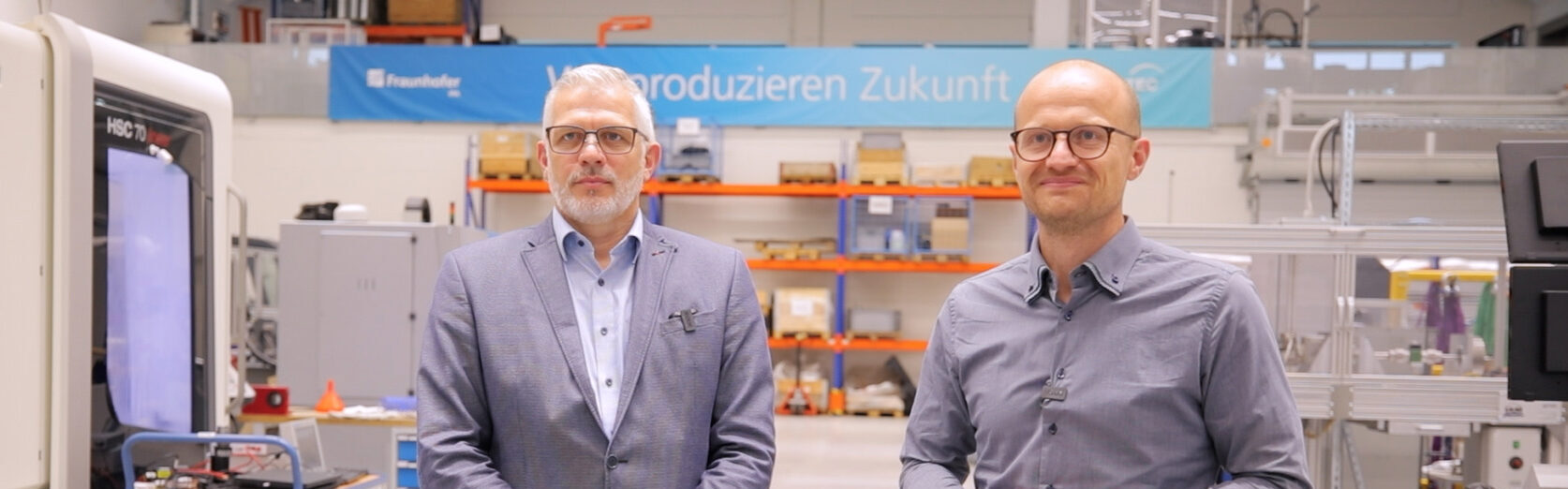 Markus Ziehl und Michael Scholz stehen in einem Versuchsfeld des Fraunhofer IPA. Beide schauen in die Kamera und haben die Hände vor dem Bauch zusammengelegt.